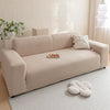 A beige jacquard velvet sofa cover displayed on a light-colored rug in a bright room.