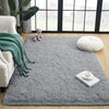 A gray tie-dyed plush floor mat with a white ceramic cup and spoon on it, placed in a bright room.
