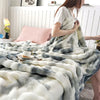A fluffy gray and white plush rabbit fur throw blanket draped over a person's arm.