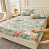 A floral fitted sheet set with green and pink flowers and matching pillowcases on a bed.