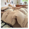 A beige ultra-soft washed cotton quilt bedding set on a bed with natural light and wooden furniture.