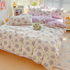 A bed dressed in a lavender print duvet cover set featuring floral patterns and matching pillows.