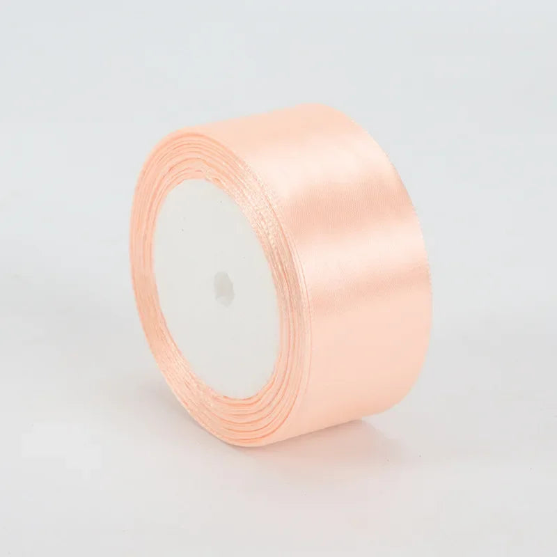 A roll of peach satin ribbon, 4cm wide, used for crafts and gift wrapping.