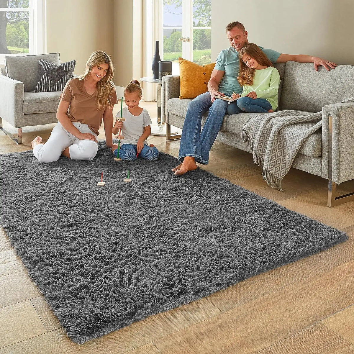 A family of three is playing on a gray tie-dyed plush floor mat in a living room.