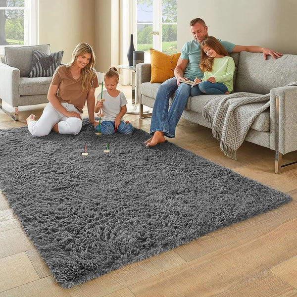 A family of three is playing on a gray tie-dyed plush floor mat in a living room.