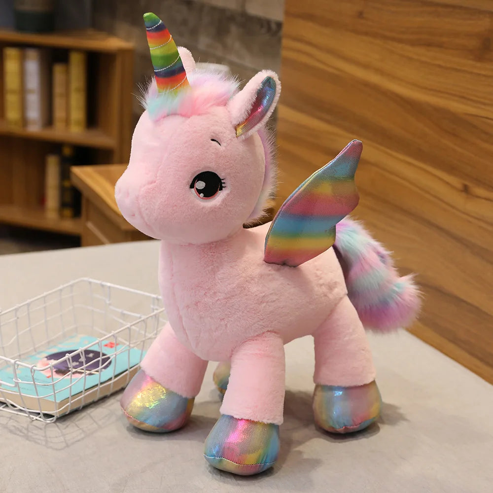 A pink unicorn plush toy with rainbow accents sitting on a light surface.