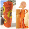 An orange-red cylindrical resin object covered in flatback rhinestones, shown next to an orange dress.