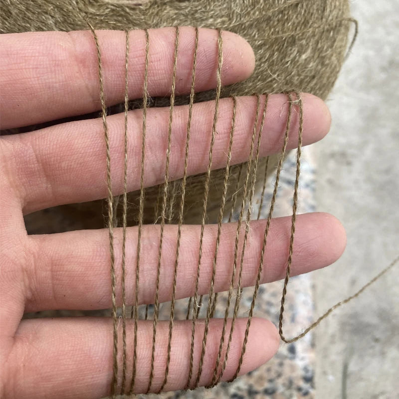 A hand is holding several strands of brown hand-woven wool and linen blended yarn.