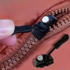 A close-up of a brown zipper with a black detachable repair kit attached to the teeth.
