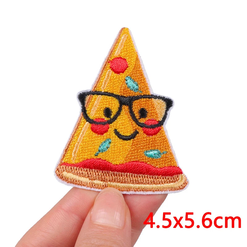 An embroidered patch shaped like a smiling cartoon cat wearing black glasses and sitting on a slice of pizza.