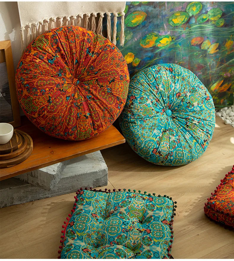 A collection of colorful bohemian cotton linen throw cushions displayed on a wooden shelf and floor.