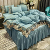 A teal bed skirt set featuring lace edge detailing and gold embroidery on a bed with light blue pillows.
