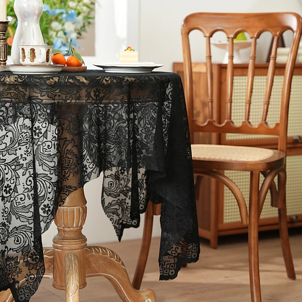 Black lace tablecloth draped over a wooden table with a wooden chair in the background.