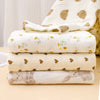 Stack of white printable cotton crib sheets with yellow floral patterns and a brown animal print sheet.