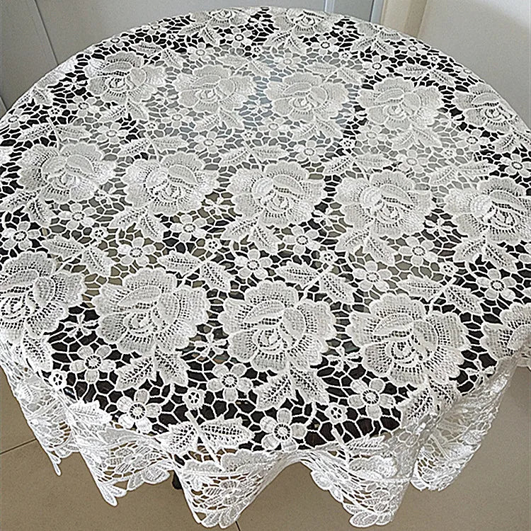 White floral lace tablecloth with scalloped edges displayed on a round table.