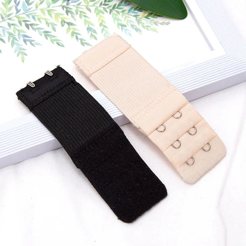 A set of adjustable bra extender straps in black and beige are displayed on a white surface.