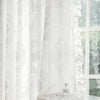 White vintage ruffled lace embroidered curtain hanging in front of a window.