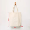 A plain off-white canvas tote bag hanging on a wooden hanger.