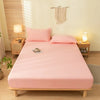 A pink fitted sheet set with a matching pillow is displayed on a wooden bed frame in a bright room.