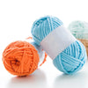 Two skeins of thick velvet yarn, one light blue and one orange, are displayed on a white surface.