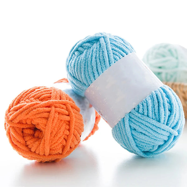 Two skeins of thick velvet yarn, one light blue and one orange, are displayed on a white surface.