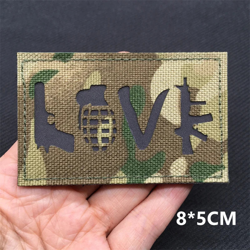 A rectangular tactical patch featuring the LOVE symbol and a globe design on a camouflage background.