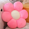A pink sunflower plush flower cushion resting on a light-colored surface.