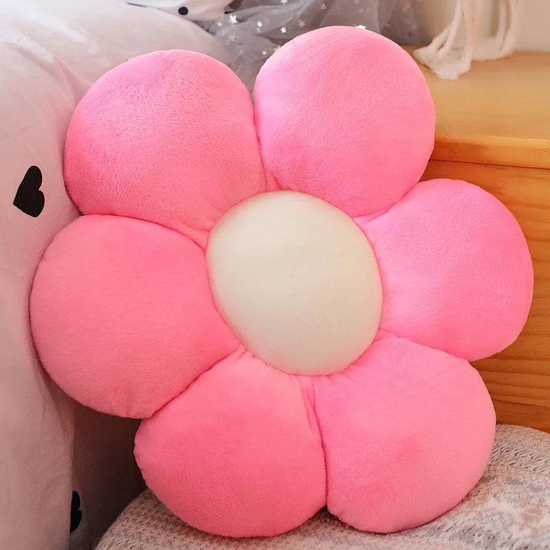 A pink sunflower plush flower cushion resting on a light-colored surface.