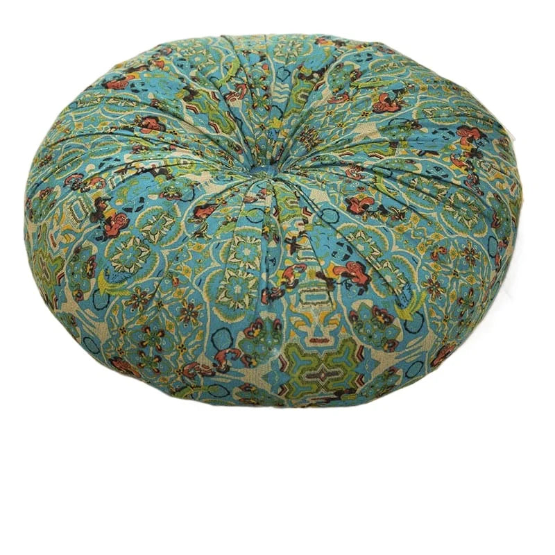 A round throw cushion with a blue and teal bohemian pattern on a light beige background.