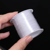 A hand is holding a spool of white precision nylon beading thread for jewelry making.