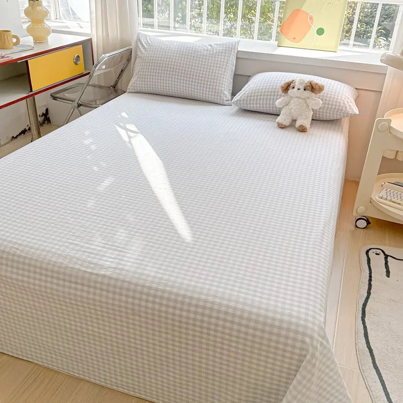 A white organic cotton bedding set with a quilted flat sheet and pillowcases displayed on a bed.