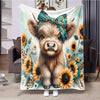 A flannel blanket featuring a Highland cow face surrounded by yellow sunflowers and green foliage.