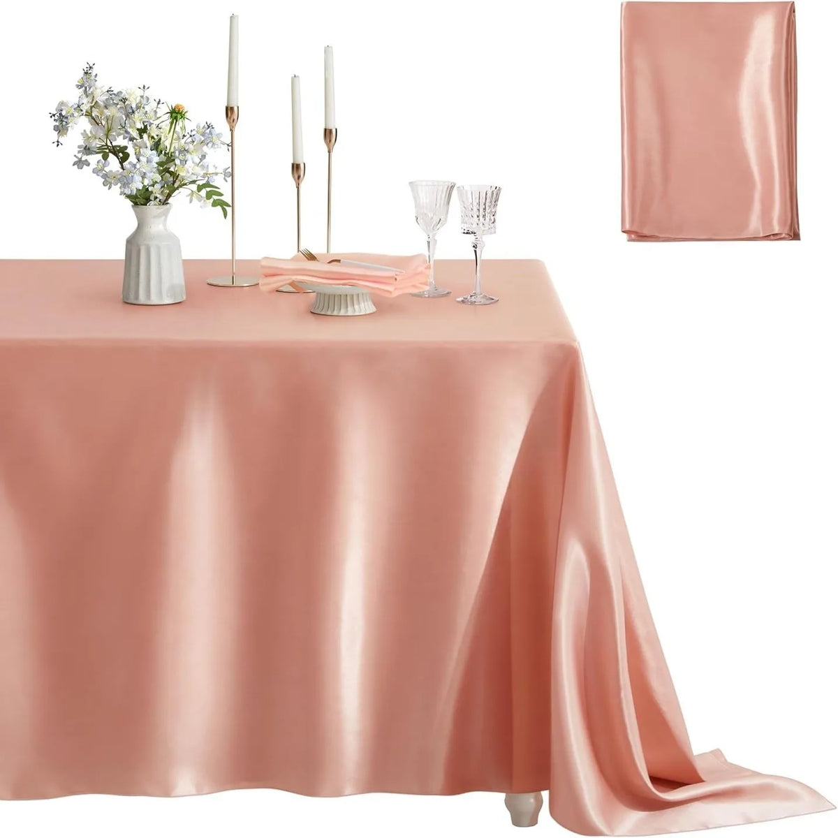 A pink satin tablecloth set for elegant dining featuring a floral centerpiece and glassware.