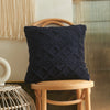 A dark navy blue textured plaid cushion cover resting on a light wood stool.