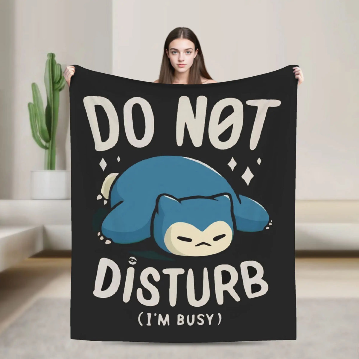 A black throw blanket featuring a cartoon blue cat face with the text DO NOT DISTURB I'M BUSY