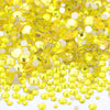 A pile of yellow and clear glass rhinestones for DIY crafts