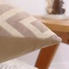 A close-up of a beige chenille jacquard throw pillowcase with a diamond pattern on a wooden surface.