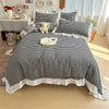 A plaid duvet cover set featuring black and white checks with lace embroidery, displayed on a bed.