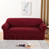 A deep burgundy stretch knit sofa cover featuring a bubble lattice texture placed on a light rug.