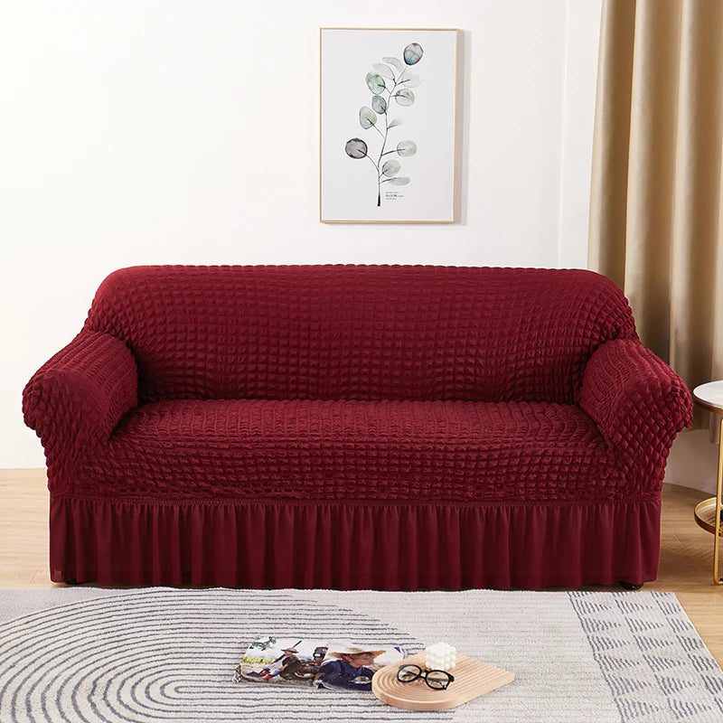 A deep burgundy stretch knit sofa cover featuring a bubble lattice texture placed on a light rug.