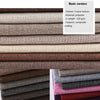 Rolls of coarse linen and cotton fabric in various earth tones and shades of gray and purple.