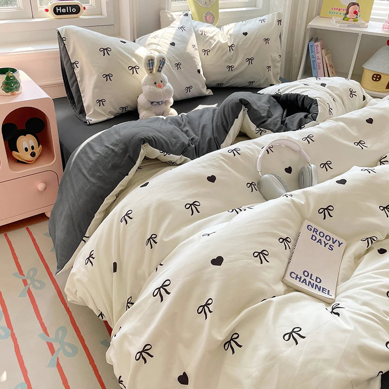 A white duvet cover set with black patterns and pillows is displayed on a bed.