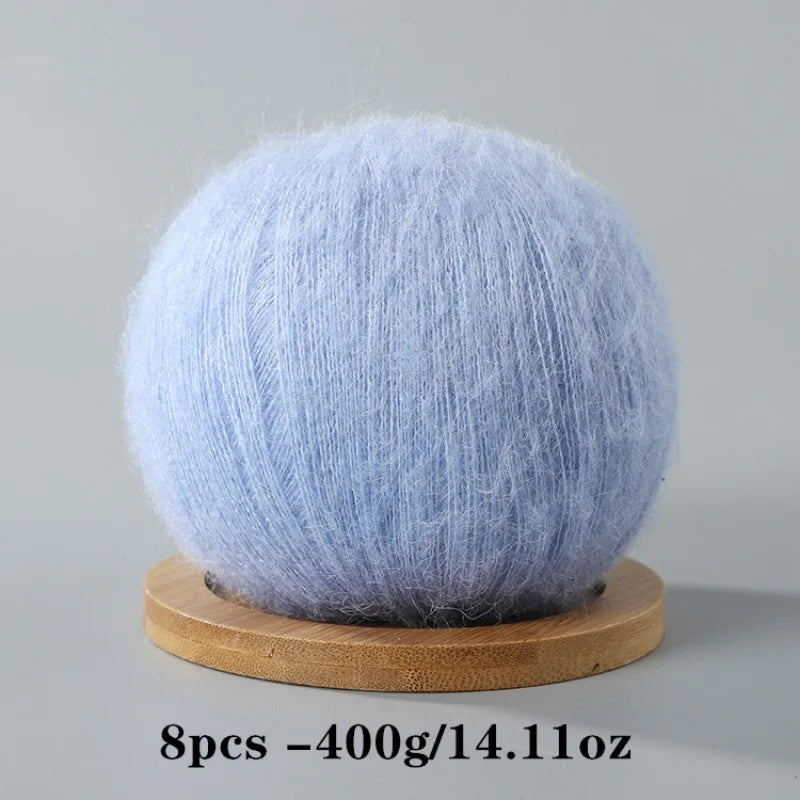 A ball of light blue fluffy mohair yarn resting on a wooden base.