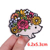 An embroidered patch of a cute cartoon bear face surrounded by colorful floral designs.