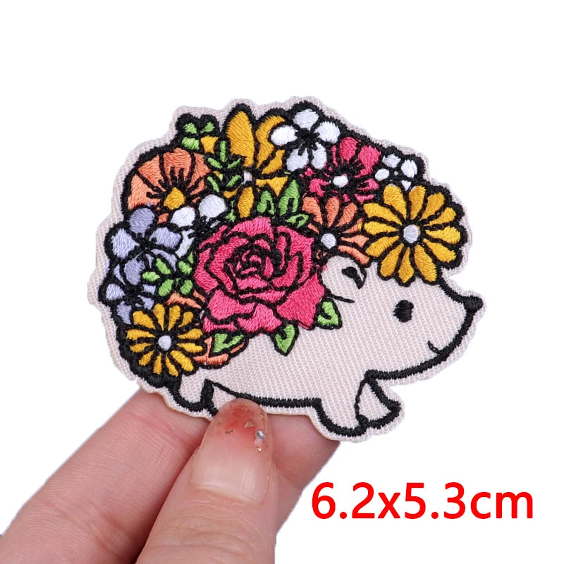 An embroidered patch of a cute cartoon bear face surrounded by colorful floral designs.