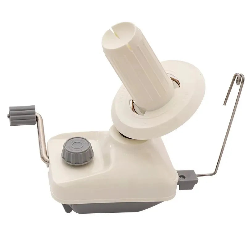 A hand operated wool yarn winder with a white and gray plastic body and a cylindrical winding mechanism.