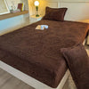 A dark brown jacquard weave fitted sheet bedding on a bed with a bedside lamp and wooden shelf.