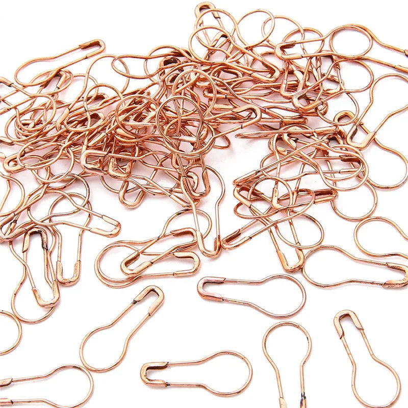 A pile of copper-colored safety bulb pins for knitting and sewing