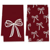 A set of two deep red kitchen towels featuring white bow patterns.