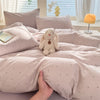 A light pink duvet set featuring a cute, fluffy rabbit plush toy on the bed.
